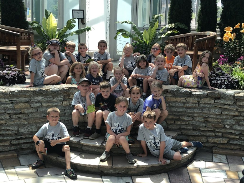 A group of school age care kids gathered on the steps of the Como Zoo Conservatory.