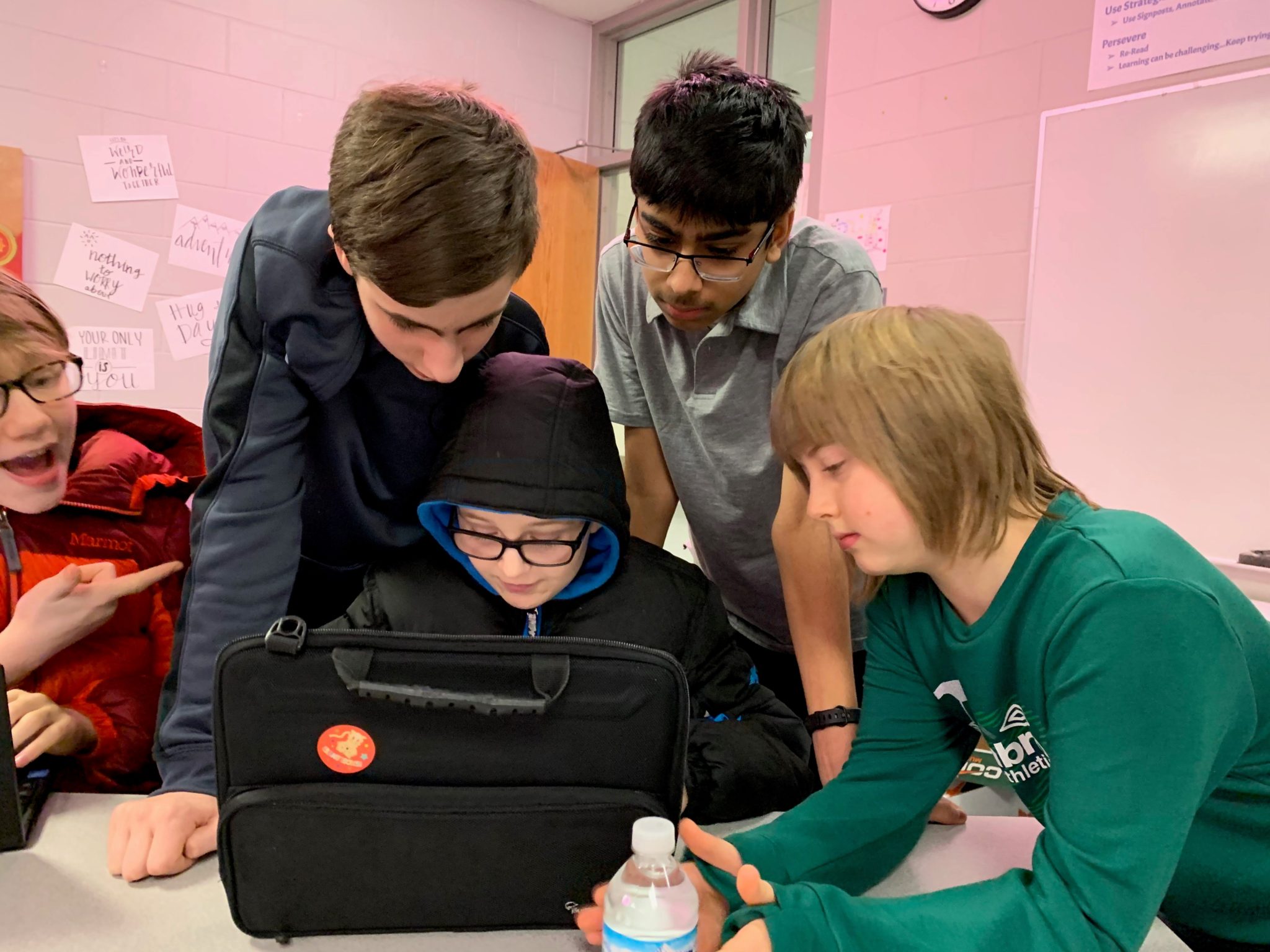 Four students work together at a laptop computer.