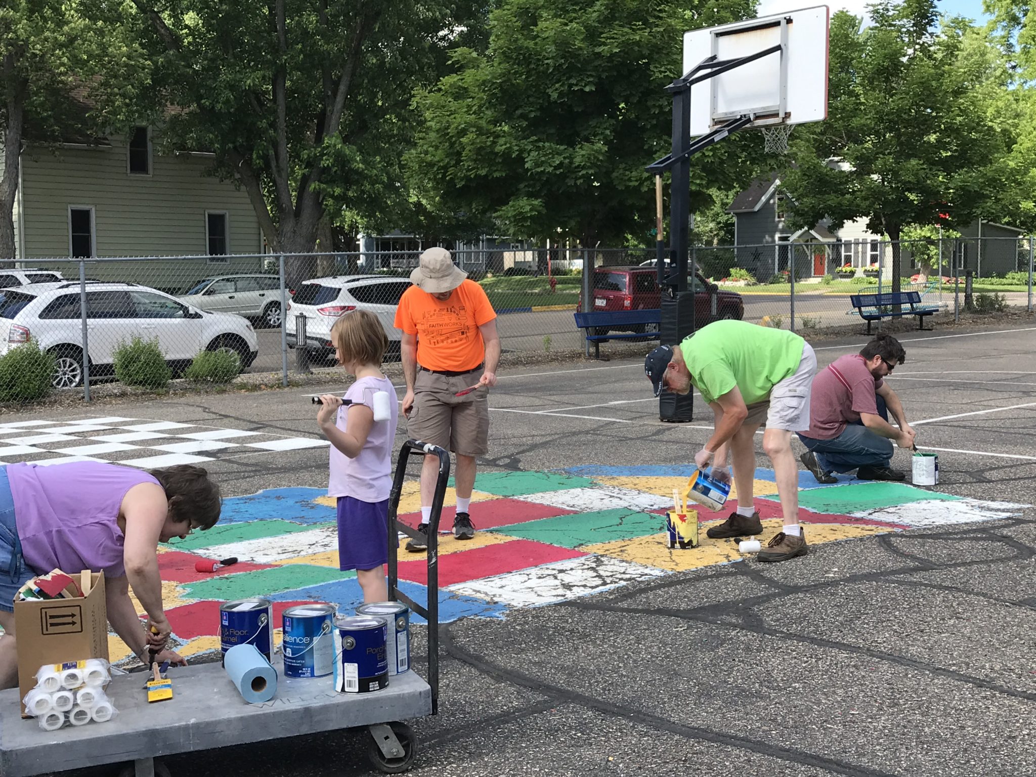 A group of children and adults painting the United States map on the playground pavement.