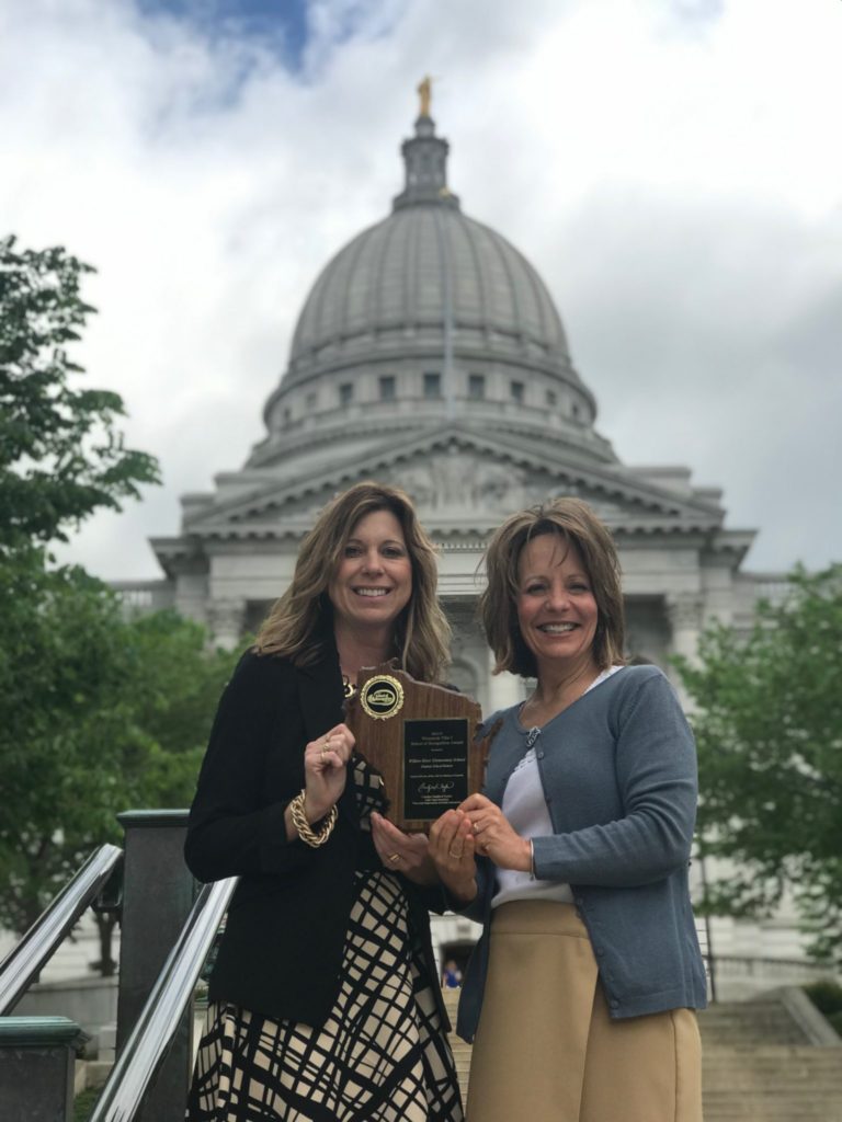 Willow River Elementary School Principal Kimberly Osterhues (left) and Willow River Elementary Reading Specialist Laurel Anfinson stand in front of the Wisconsin state capitol building with the school's Title One Recognition Award.