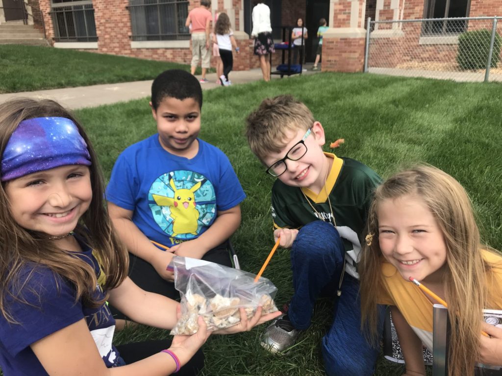 A group of students are outside looking at a bag of geodes.