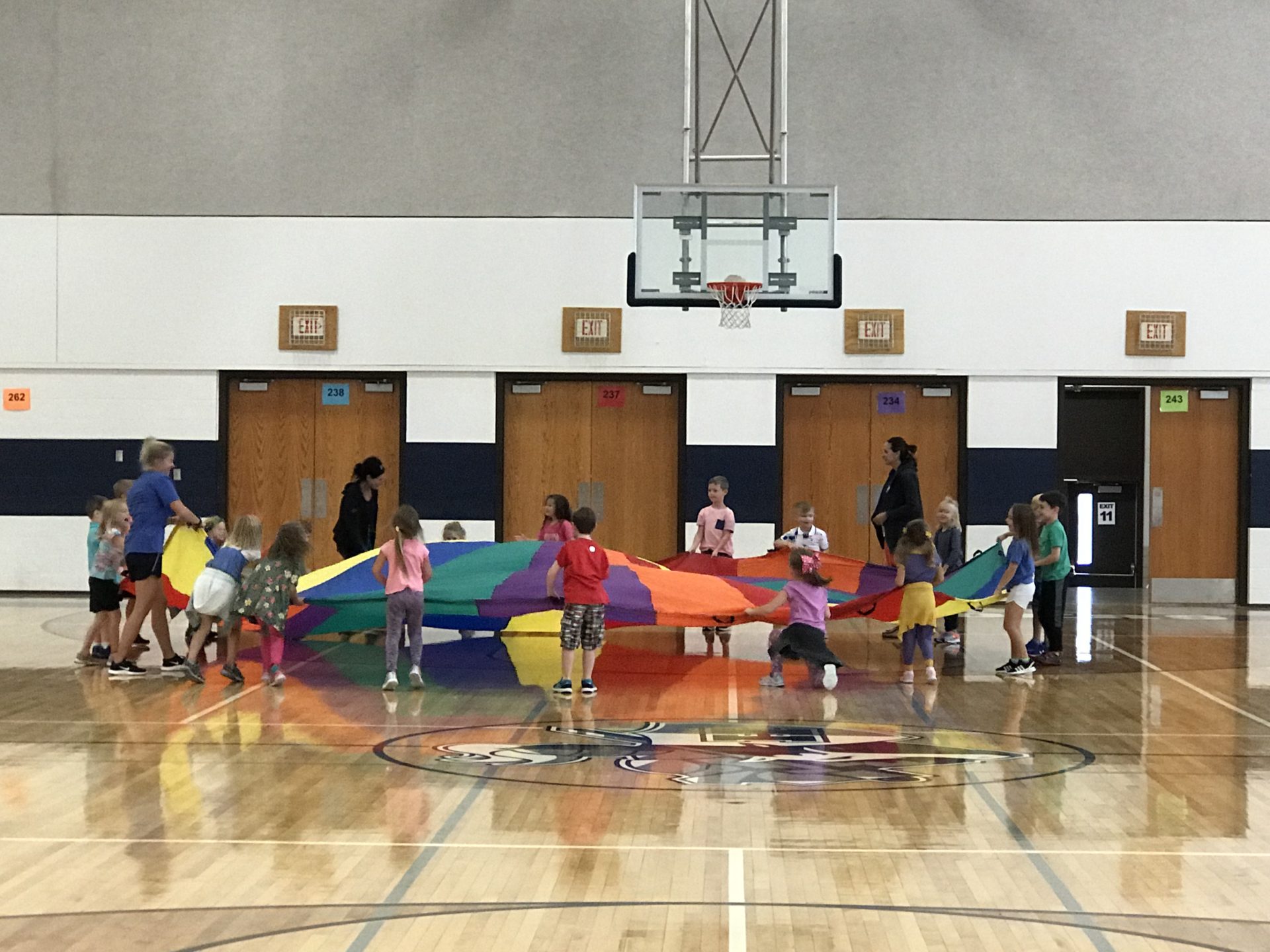 A group of children in a circle holding on to a parachute.