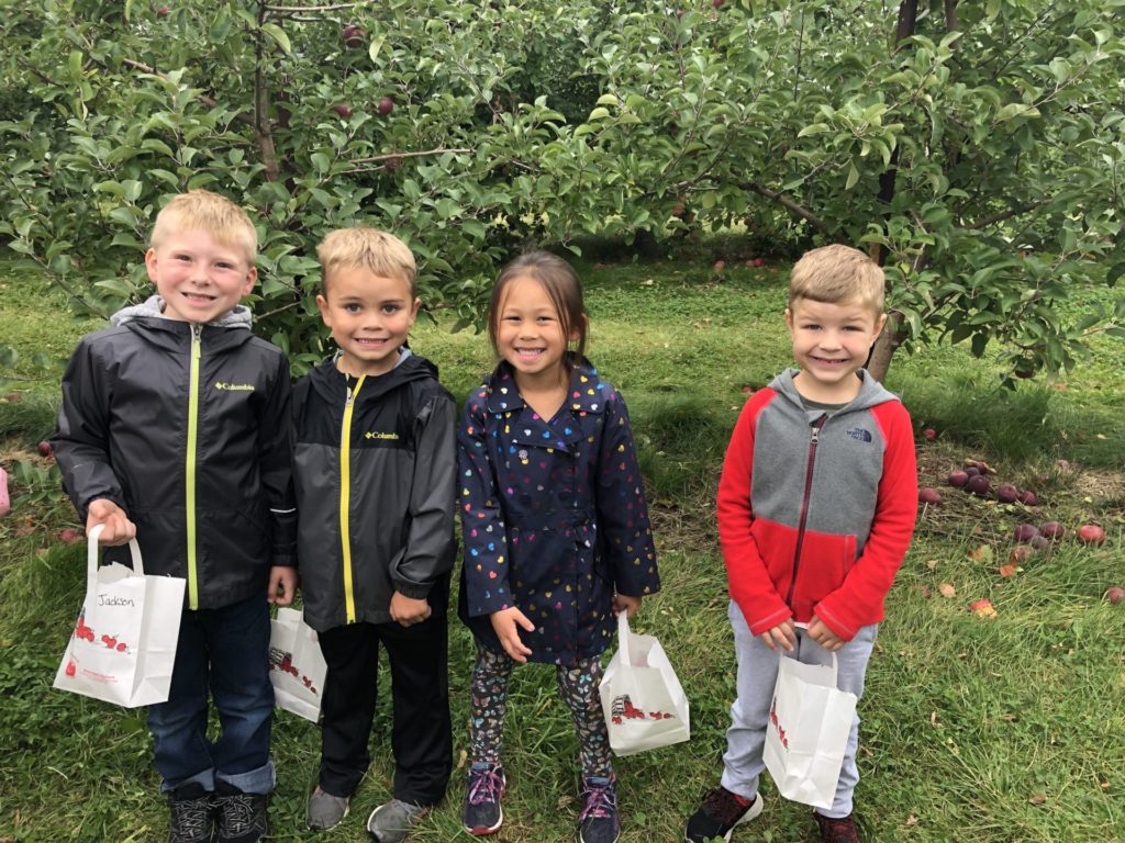 Four North Hudson kindergarteners at the apple orchard with bags of apples.