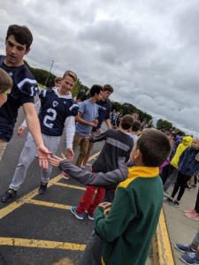 Elementary students meet high school football team and pep band members.