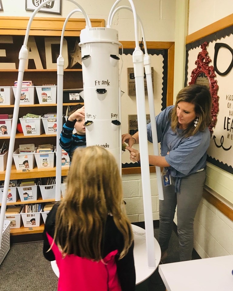 Two students and a teacher assemble a tower garden.