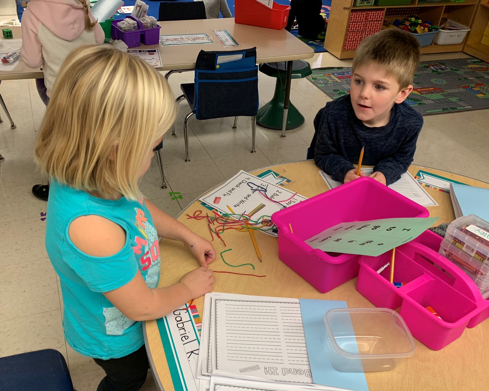 Two students working on a table with the letter station activity.