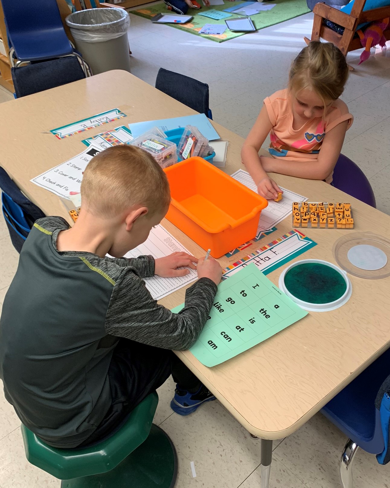 Two students working on a table with the letter station activity.