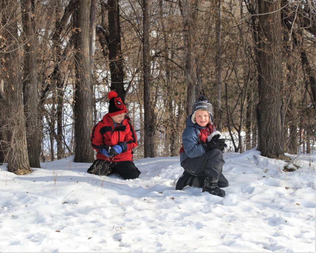 Two boys in the snow by the edge of the school forest.