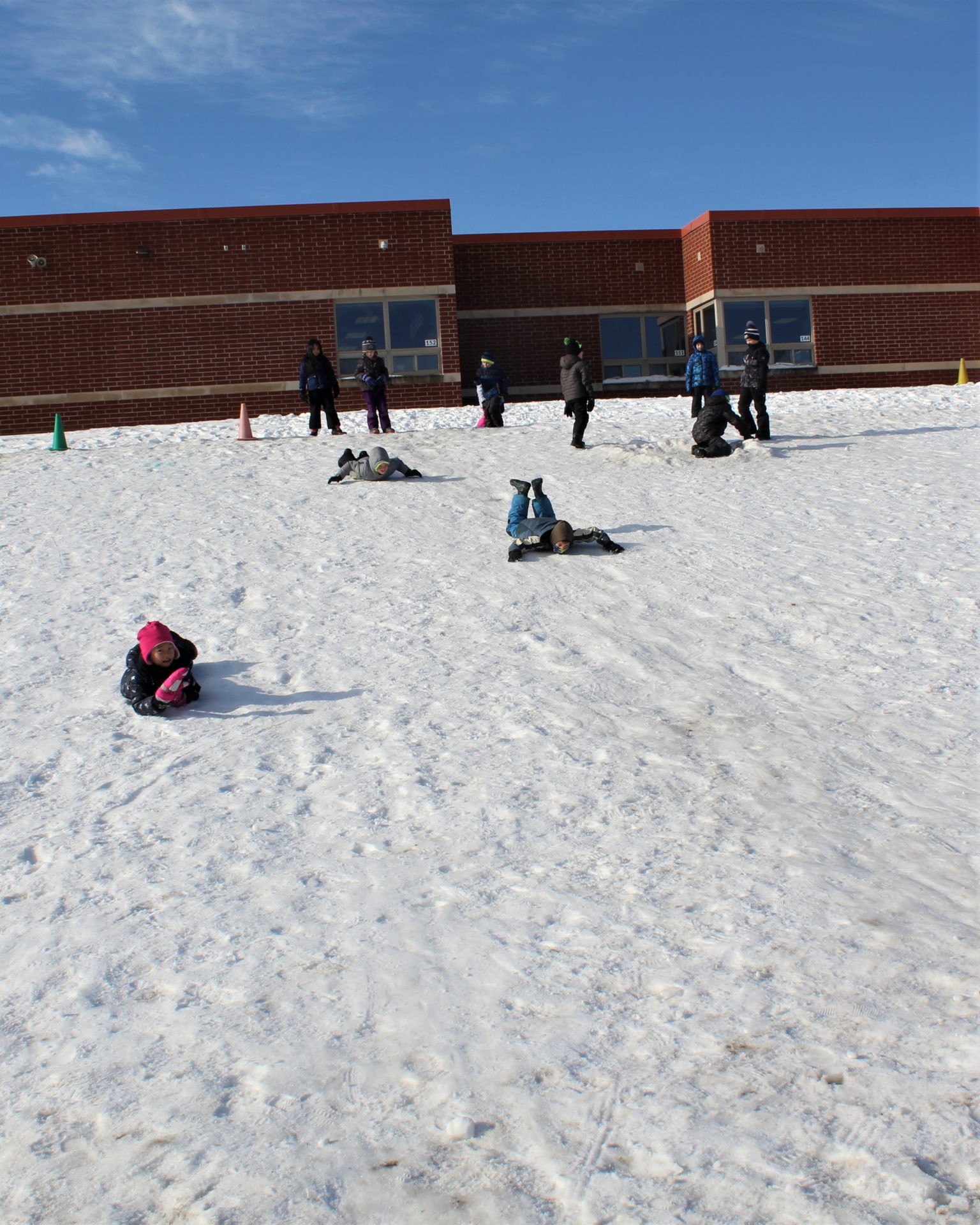 A group of children sliding down the hill.