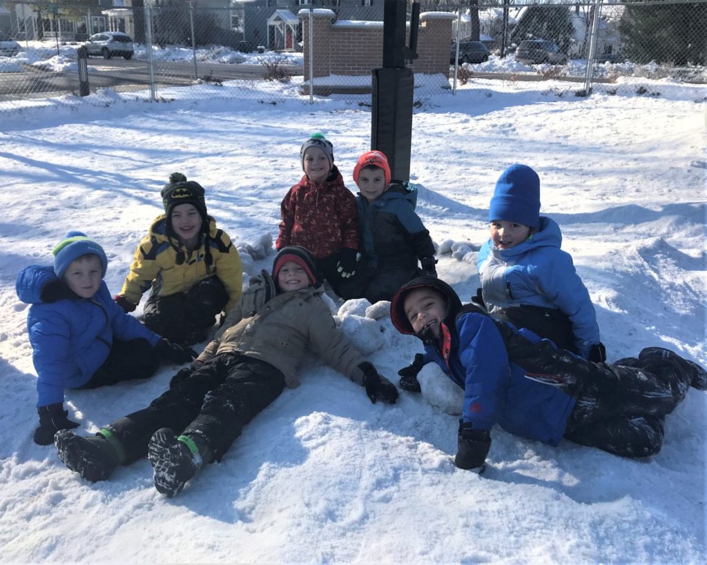 A group of children gathered on a snow pile.