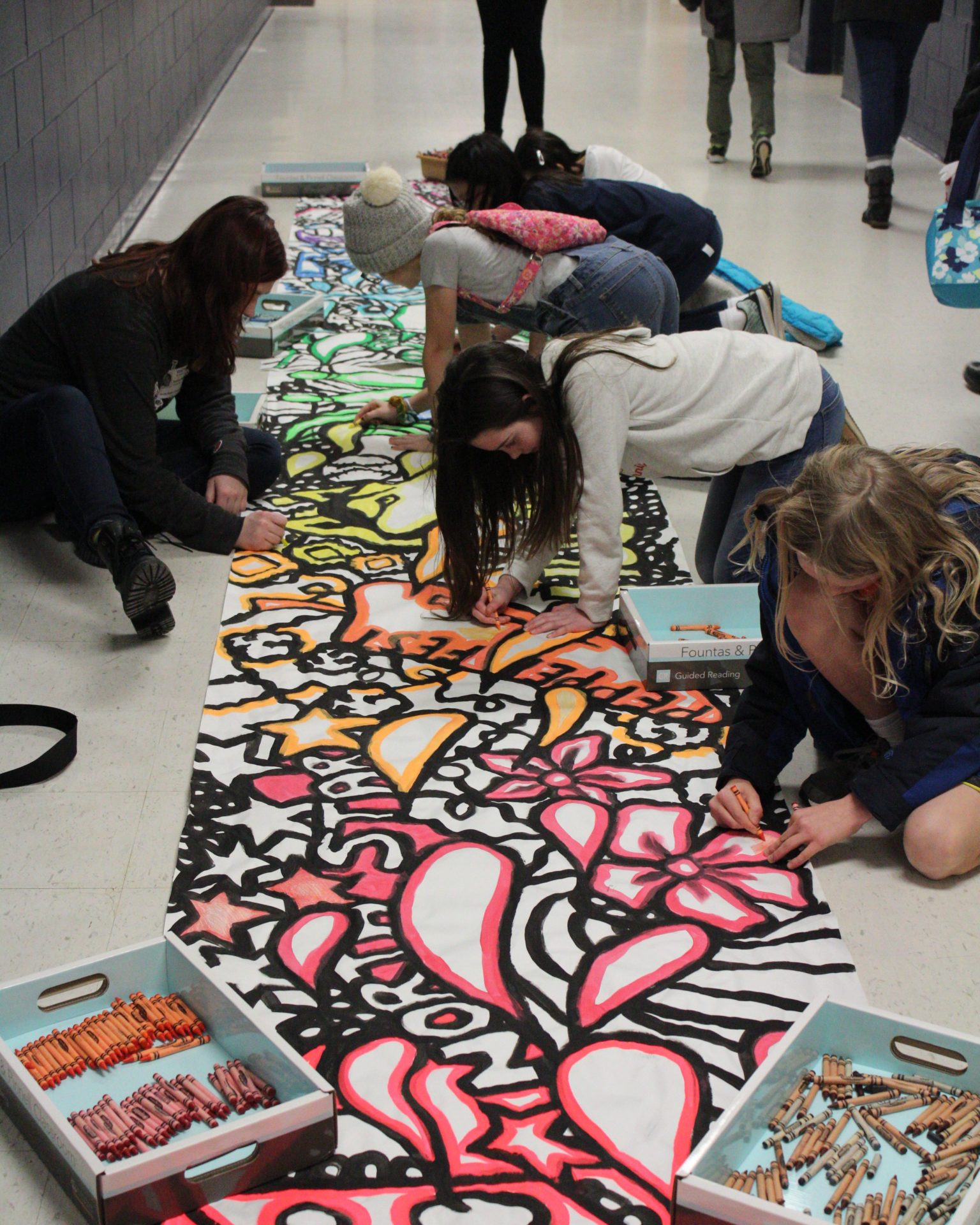 Students coloring on the floor banner.