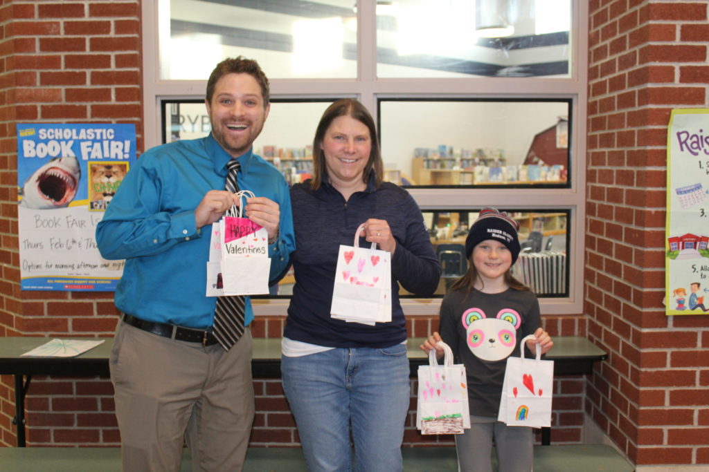 A group of students and adults show their Valentines bags.