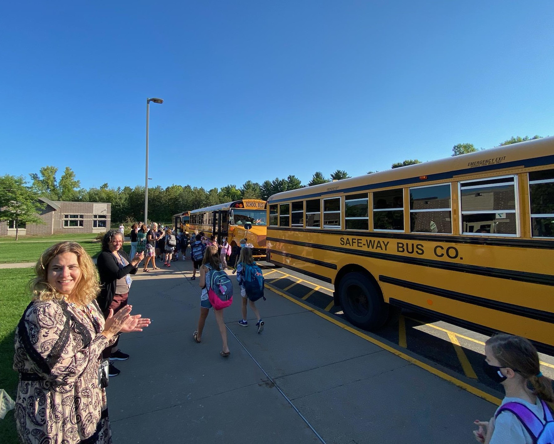 Teachers greeting students as they get off the bus.