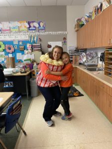 A student and teacher hug during Popcorn Fridays.