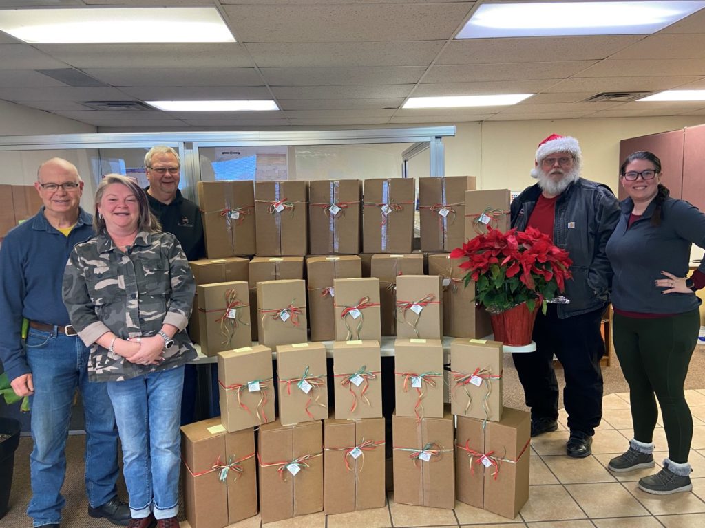 A group of bus drivers stand with a pile of gift boxes.