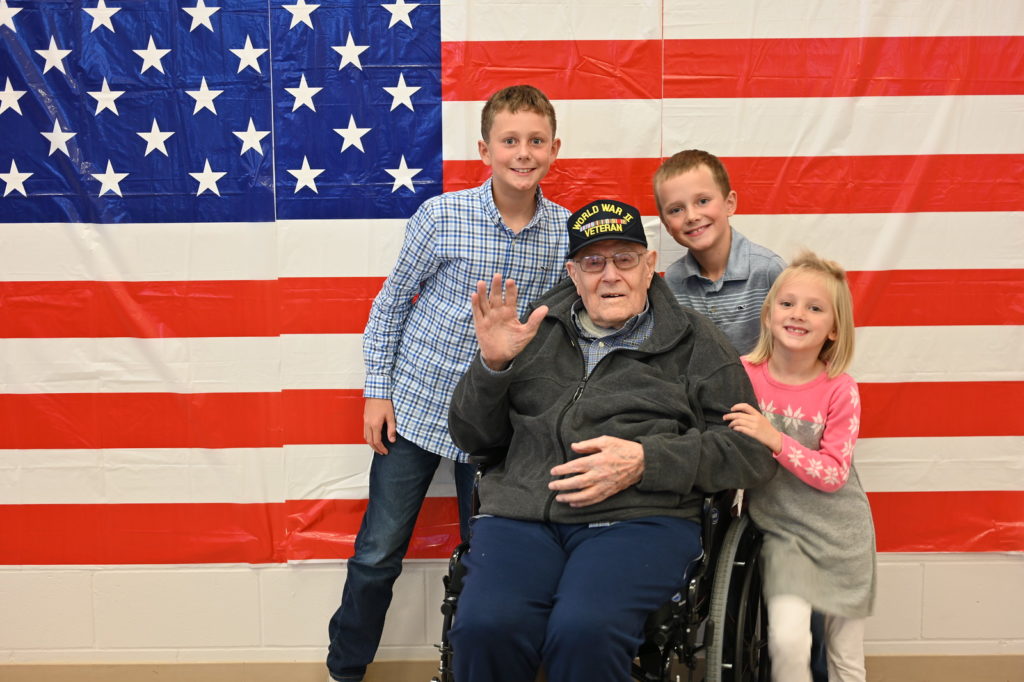 Students pose with a veteran in a wheel chair.