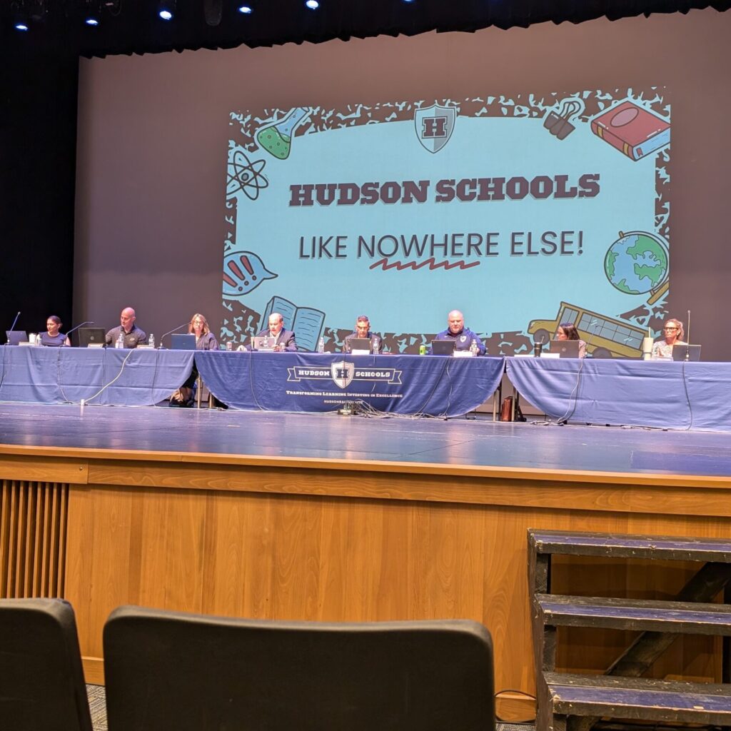 Board of Education sitting on the stage at the Hudson High School auditorium