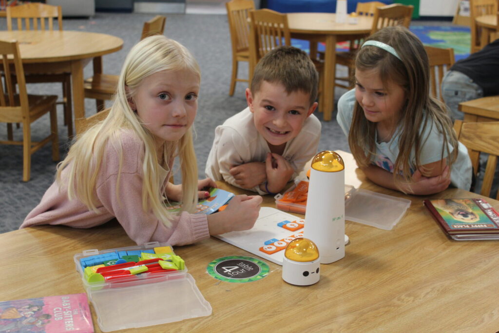 Three students working at the media center table.